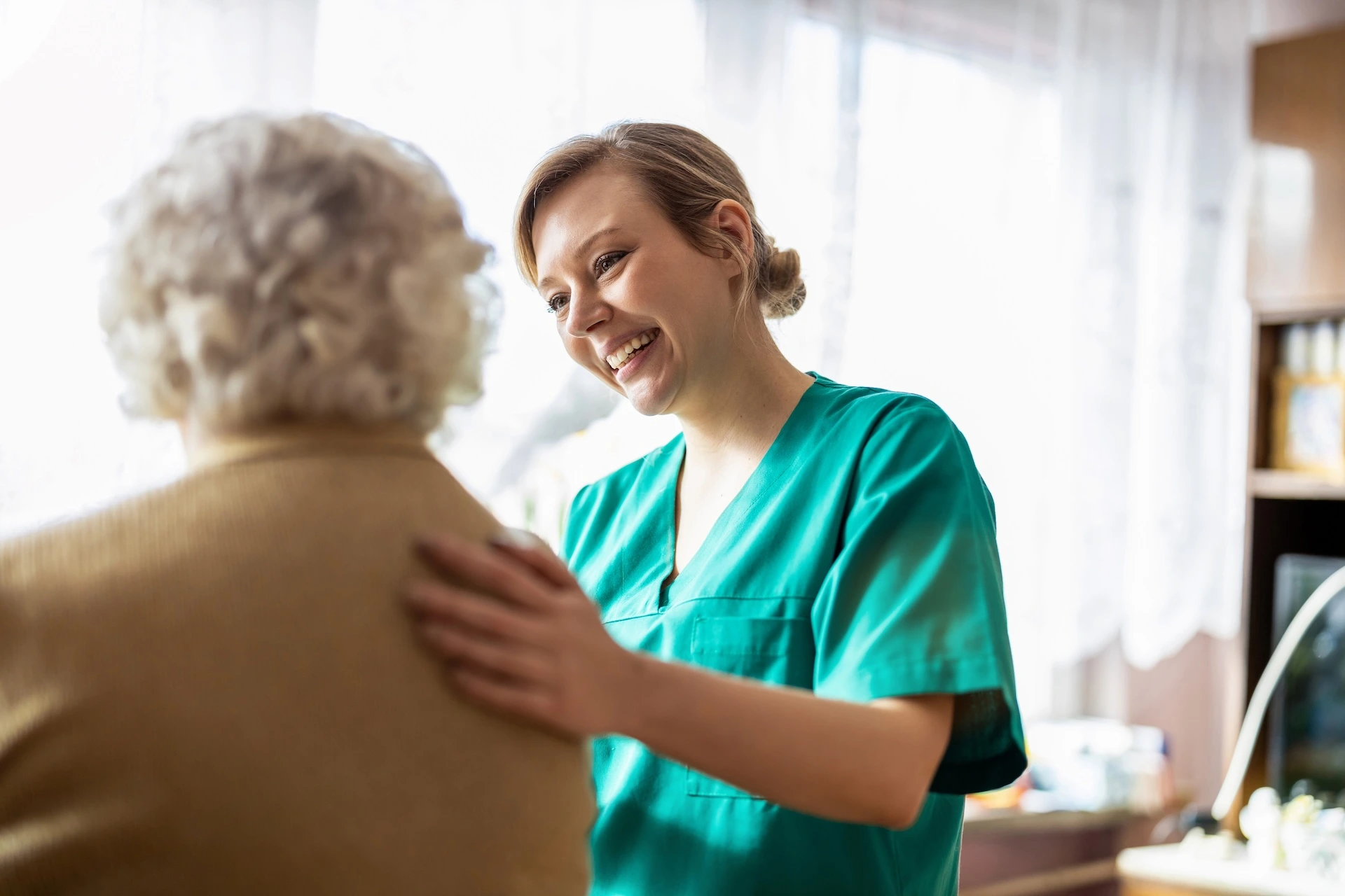 Nurse with her hand on the back of an elderly lady for reassurance