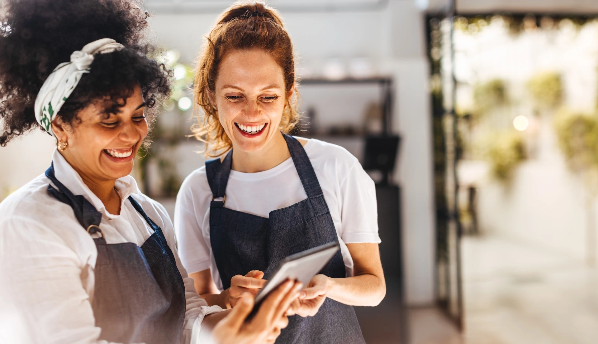 Two hospitality workers smiling and looking at an ipad