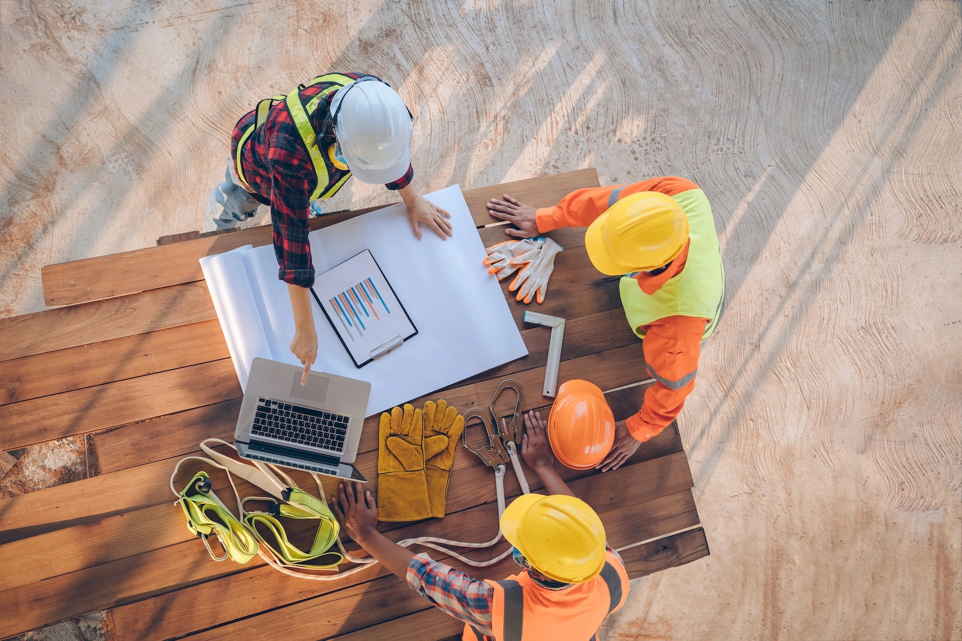 Construction workers at a makeshift table pointing at a laptop screen